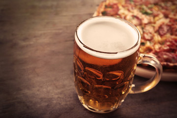 Tasty pizza and glass of beer are on wooden table, close up