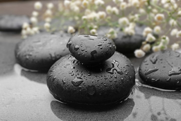 Beautiful spa composition with wet stones and flowers on grey background