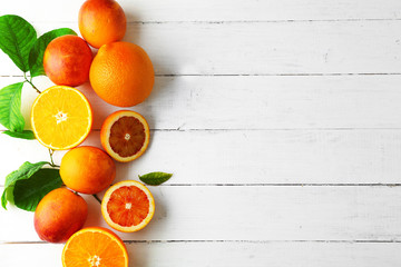 Different kinds of oranges on white wooden table