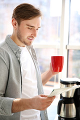 Young handsome man with cup of coffee in the kitchen