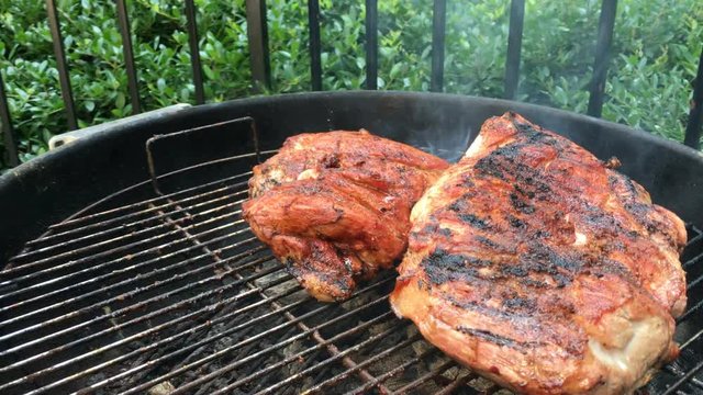 Pork shoulder grilling on a charcoal grill