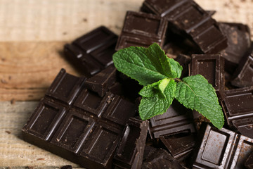 Chocolate pieces and mint on wooden background