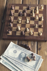 pawn, chessboard game and banknote on wooden table, vintage tone