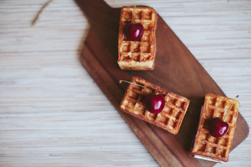 waffles with a cherry on a wooden board