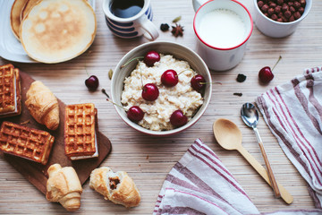 rich breakfast of porridge with cherries and pastry