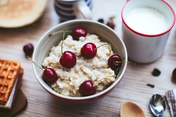 rich breakfast of porridge with cherries and pastry