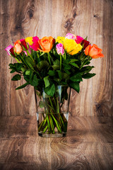 Roses in the vase on wooden background
