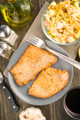 overhead take fillet breaded veal and cold salad; on wood