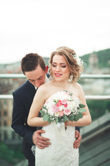 Beautiful couple, bride and groom posing on balcony with backgrounf of old city