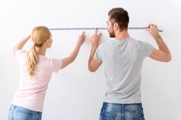 Young couple measuring wall