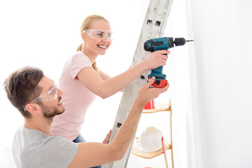 Smiling boy helping girl to keep drill