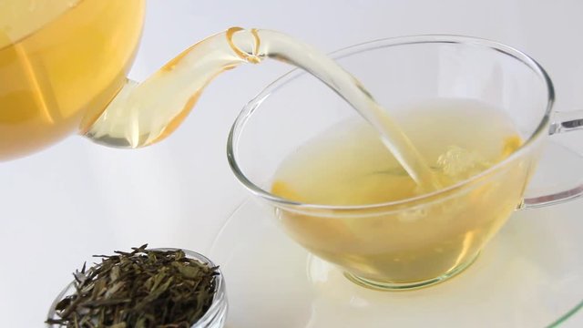 Bef&uuml;llen einer Glastasse mit gr&uuml;nen Tee