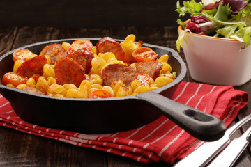 Casserole with chorizo sausage on wooden background