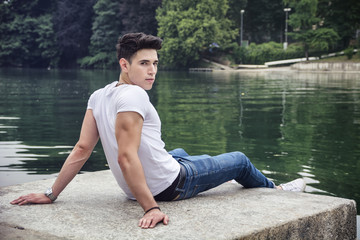 Fototapeta na wymiar Contemplative young man sitting beside river
