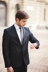 Confident businessman looking on his wrist watch in suit