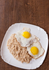 oatmeal porridge with fried egg in a plate on wooden table
