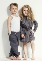 Funny lovely children. Fashionable little boy and girl in grey and white clothes and  barefoot....