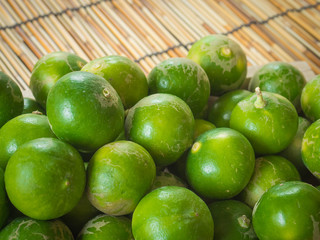 Box with green lemons on a Wood Bamboo Mat