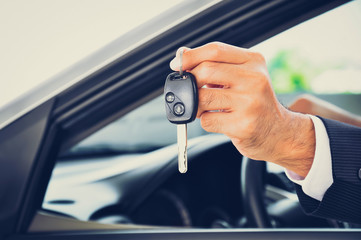 Hand holding a car key - car sale & rental business concept