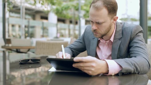 Businessman sitting at outdoor cafe and takes notes