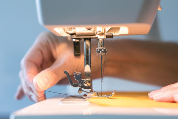 Women's hands at work with the sewing machine - obrazy, fototapety, plakaty