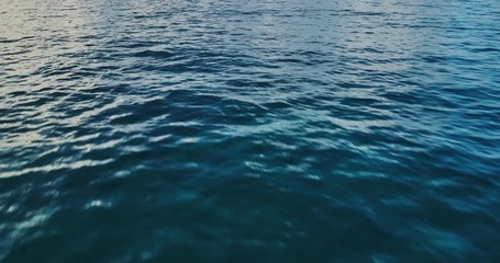 Flying over ocean at sunrise, aerial view flying over water into clouds