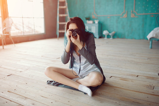 Portrait of pretty young girl taking picture on film camera