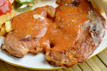 grilled pork steak dressing gravy and french fried on plate