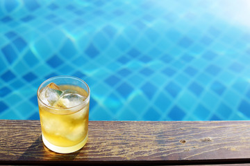 A short glass of ice beer at pool with vintage filter background
