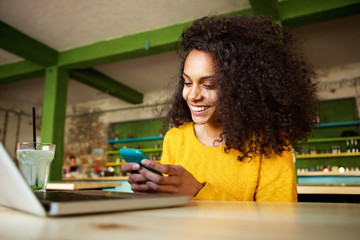 Cheerful young woman using mobile phone in a cafe