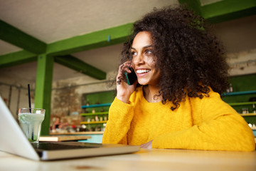 Happy young woman in cafe making phone call