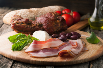 Smoked bacon with bread, mozzarella, olives and basil