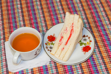 White cup of tea with Imitation crab Stick  sandwich on the white disc