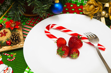 New Year Christmas tablecloth with a pattern of Santa Claus, CHRISTMAS HOLLY, gifts, a fork with a plate of fresh strawberries and candy