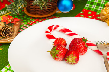 New Year Christmas tablecloth with a pattern of Santa Claus, CHRISTMAS HOLLY, gifts, a fork with a plate of fresh strawberries and candy