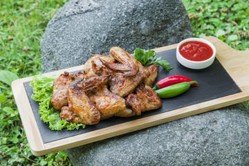 Grilled chicken wings in nature on a rock