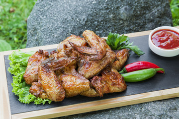 Grilled chicken wings in nature on a rock