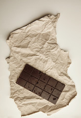 Freshly baked rustic healthy chocolate bar with nuts on craft paper, isolated on white table on side, top view, space for your text