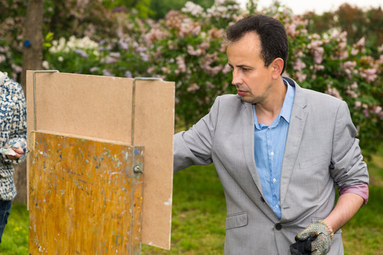 Pensive middle-aged male artist standing in front of his sketch