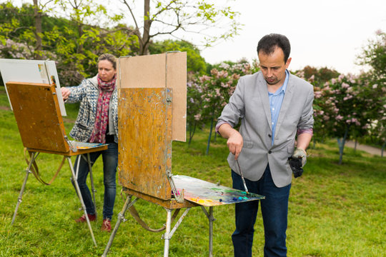 Pensive middle-aged male and female artists standing in front of