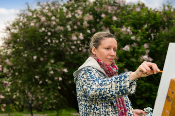 Female middle-aged contemplative artist working  on a trestle in