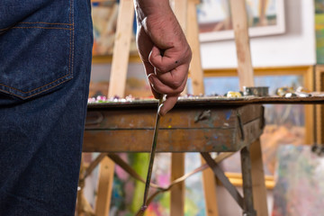 Male artist  hand holding a tiny paintbrush