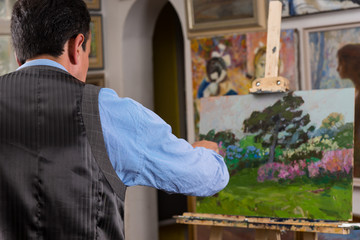 Male painter working on an easel in a gallery