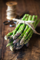 Bundle of fresh asparagus stalks on dark rustic wooden table