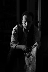 Black and white portrait of male artist holding  paintbrushes