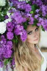 Naklejka premium Young beautiful woman posing with spring flowers. Gorgeous natur