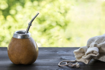 yerba mate in gourd matero with linen bag on wooden table