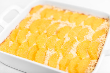 Pie with oranges in the baking dish on a white table