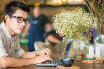 Handsome young asian student man working on laptop and smiling