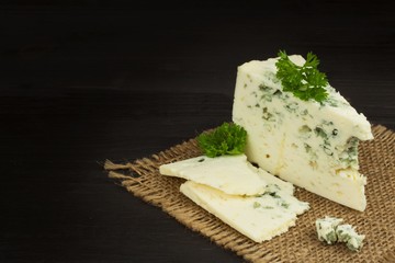 Danish blue. Blue cheese close up on an old wooden table. Preparing food blue cheese. Cheese on the kitchen table. Noble rot. Cheese with mold delicacy.
